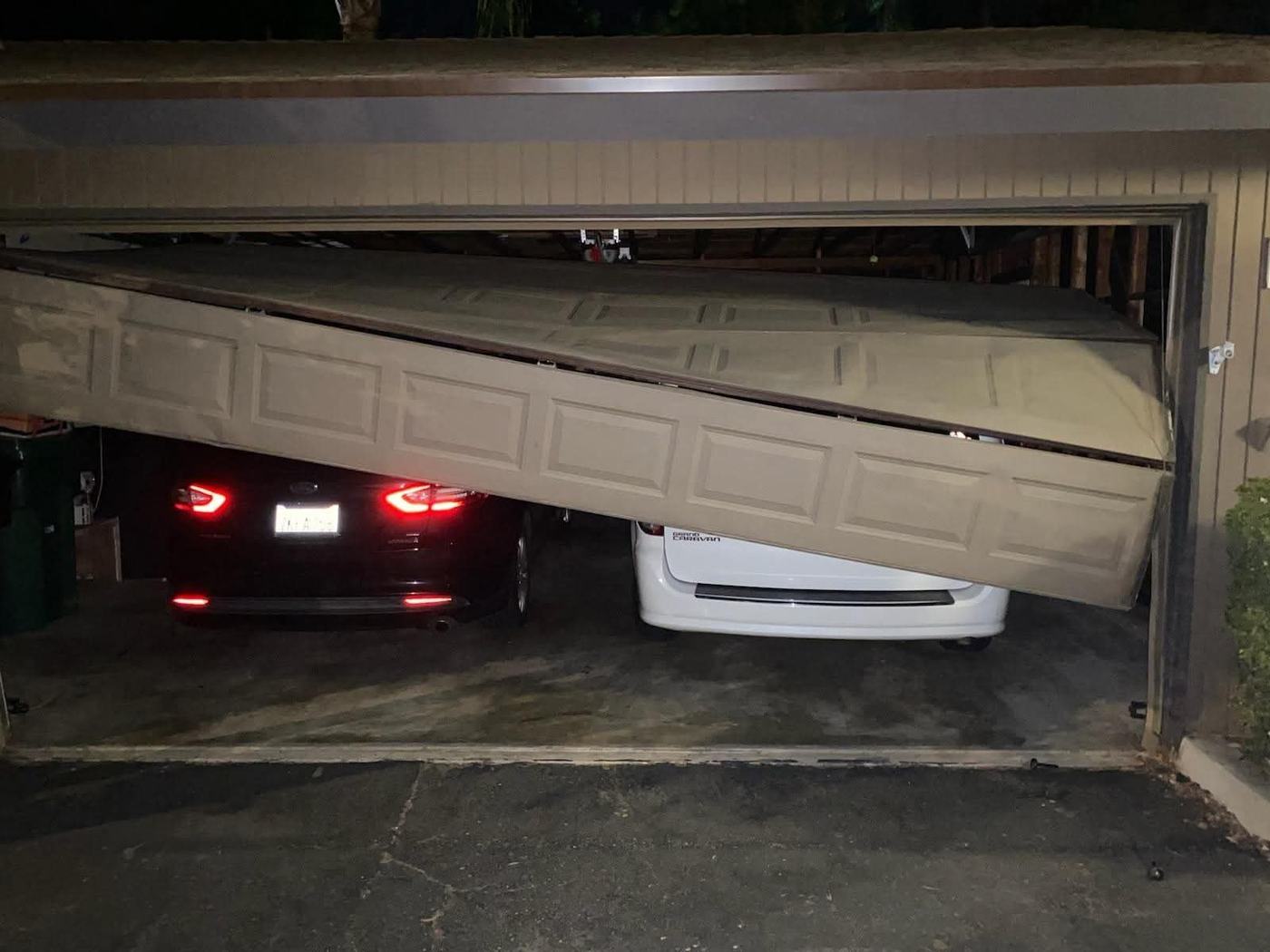 Garage door hanging off its track at night after a cable failure