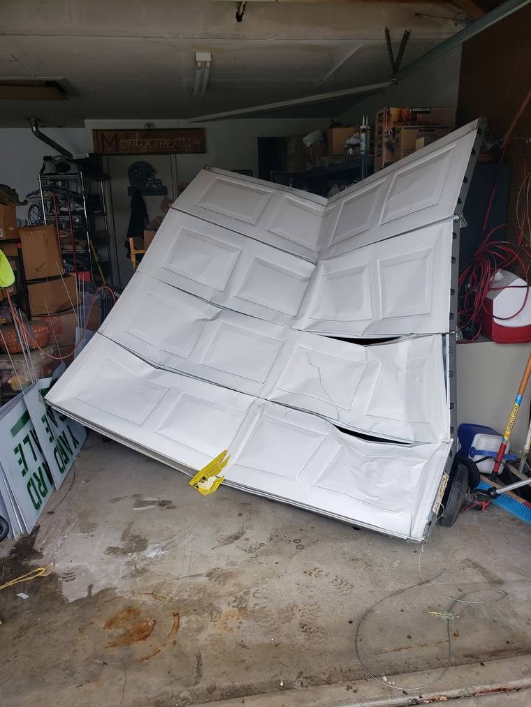 Buckled garage door panels after a torsion spring failure