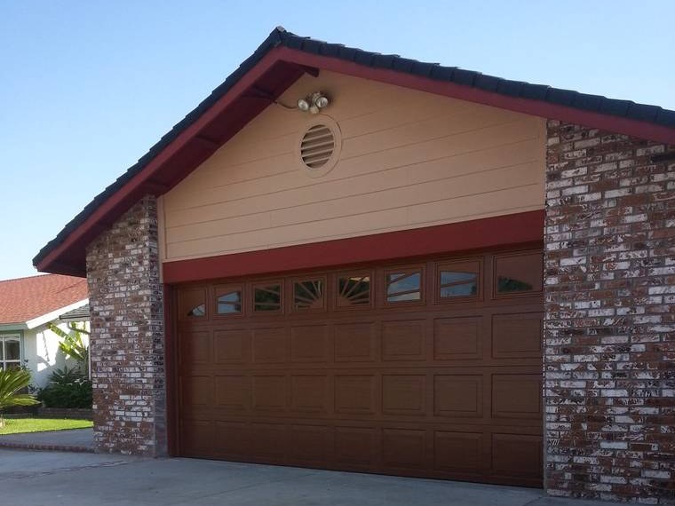 Brown steel garage door with a row of windows, between brick pillars — installed and serviced by Riverside Classic Garage Doors across Riverside County, California