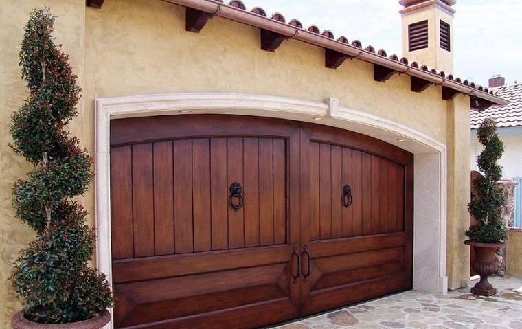 Arched mahogany carriage garage door with ring pulls on a Mediterranean elevation