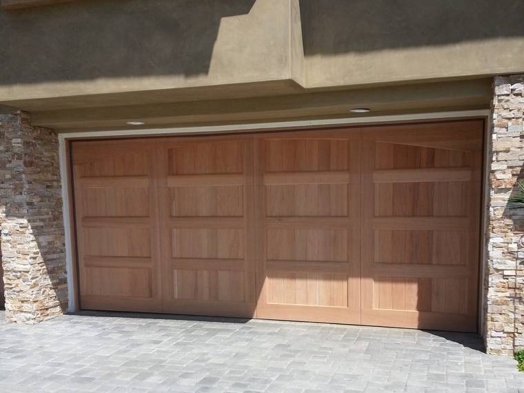 Cedar carriage-style garage door between stacked-stone pillars &mdash; installed and serviced by Riverside Classic Garage Doors across Riverside County, California