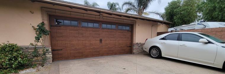 Walnut wood-grain steel door seen from the driveway
